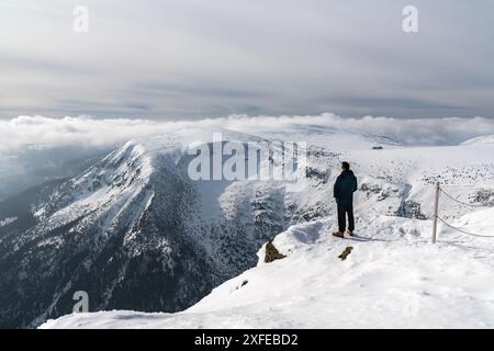 Aktive Menschen in der Natur. Ein männlicher Tourist genießt die Aussicht während eines Spaziergangs durch die schneebedeckten Berge. Karpacz, Sniezka, Polen Stockfoto