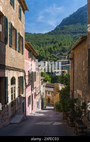 Atemberaubende Stadtlandschaft der kleinen Küstenort Deia auf Mallorca, Spanien. Traditionelle Häuser in Terrassen auf den Hügeln umgeben von grünen Bäumen entfernt Stockfoto