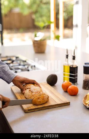 Brot auf Holzbrett schneiden, Mann, der Essen in moderner Küche zubereitet, Kopierraum Stockfoto