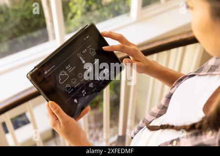 Mit Tablet, Frau, die das Smart Home System mit verschiedenen Einstellungen steuert Stockfoto