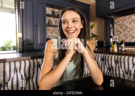Lächelnde Frau, die am Küchentisch sitzt und ihre Zeit zu Hause genießt Stockfoto