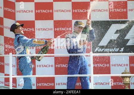 Aktenfoto vom 10-07-1994 von Michael Schumacher (links), der Damon Hill mit Champagner besprühte, bevor er später vom Großen Preis von Großbritannien 1994 disqualifiziert wurde. Ausgabedatum: Mittwoch, 3. Juli 2024. Stockfoto