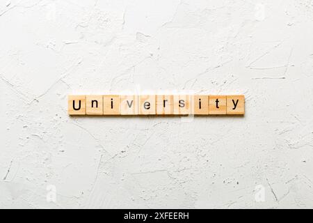 UNIVERSITÄT Wort auf Holzblock geschrieben. UNIVERSITÄTSTEXT auf Zementtisch für Ihr Design, Konzept. Stockfoto