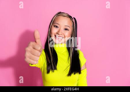 Foto von positivem Mädchen mit gefärbtem Haar gekleidetem gelben Rollkragen, das Ihnen Daumen oben zeigt gute Arbeit isoliert auf rosafarbenem Hintergrund Stockfoto