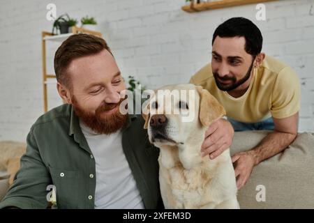 Ein bärtiger Mann sitzt auf einer bequemen Couch, streichelt sanft einen Labrador, zeigt Zuneigung und schafft eine herzerwärmende Szene. Stockfoto