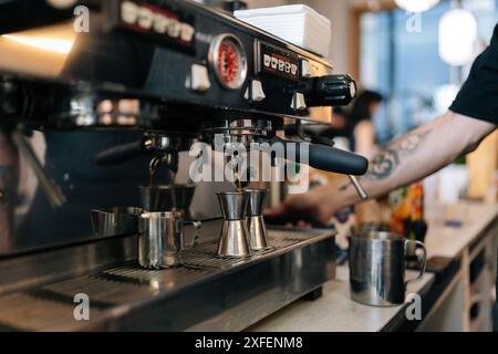 Nahaufnahme eines nicht erkennbaren Barista-Mannes, der leckeres Kaffeegetränk für Gäste in einem Café für kleine Unternehmen zubereitete. Espresso-Kaffee als Kaffee zubereiten Stockfoto