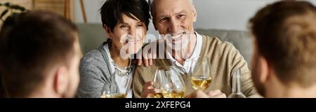 Fröhliche Eltern essen mit ihrem Sohn und seinem Partner bei einem gemütlichen Abendessen zu Hause. Stockfoto