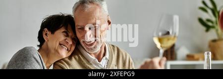 Fröhliche Eltern essen mit ihrem Sohn und seinem Partner bei einem gemütlichen Abendessen zu Hause. Stockfoto