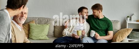 Ein schwules Paar sitzt auf einer Couch mit Eltern und genießt ein angenehmes Gespräch. Stockfoto
