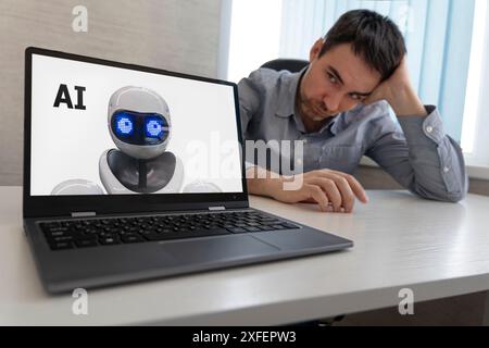 Einen Menschen durch künstliche Intelligenz ersetzen. Der Mitarbeiter sitzt an seinem Arbeitsplatz und schaut auf einen Laptop mit einem Roboter auf dem Bildschirm. Entlassung von Stockfoto