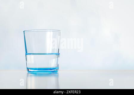 Klar und Glas Wasser. Blaues Glas mit klarem Wasser auf blauem Hintergrund. Kopierbereich Stockfoto