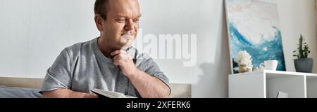 Ein Mann mit Inklusivität sitzt auf einem Bett mit Stift in der Hand und blickt nachdenklich nach unten. Stockfoto