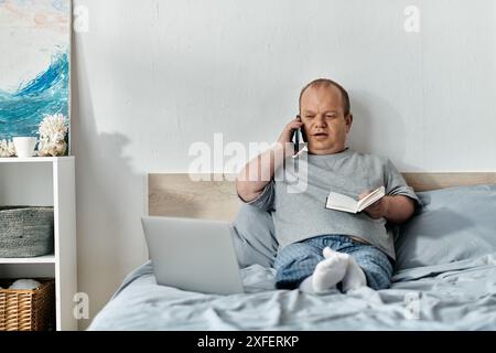 Ein Mann mit Inklusivität sitzt im Bett, spricht am Telefon und macht Notizen in einem Notizbuch. Stockfoto