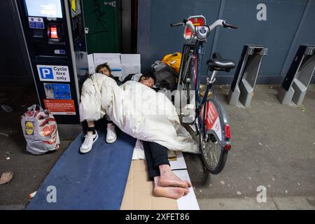 Obdachlose Drogenabhängige, rauer Schlaf unter Santander Leihfahrräder, bekannt als Boris Bikes, vor der Waterloo Station, London, England, Großbritannien Stockfoto