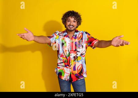 Porträt des netten jungen Mannes Arme begrüßen Sie tragen Hemd isoliert auf gelbem Hintergrund Stockfoto