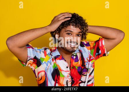 Porträt des netten jungen Mannes berühren lockiges Haar tragen Hemd isoliert auf gelbem Hintergrund Stockfoto