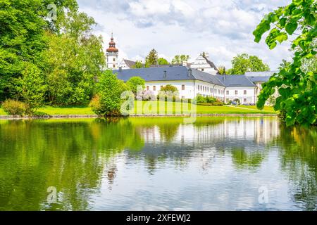 Ein malerischer Blick auf das Schloss Velke Losiny in Tschechien, mit dem wunderschönen weißen Gebäude, das sich in einem ruhigen Teich spiegelt, umgeben von üppigem Grün. Stockfoto