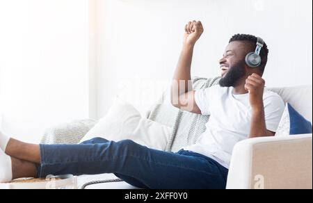 Glücklicher Mann, Der Musik Auf Der Couch Im Wohnzimmer Hört Stockfoto