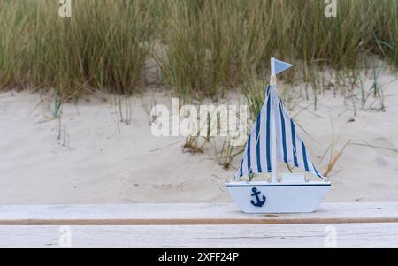 Weiße Yacht auf einer leichten Bank vor dem Hintergrund der Sanddünen. Postkarte im Marine-Stil. Ich wünsche Ihnen einen schönen Urlaub. Stillleben. Urlaub und Summ Stockfoto