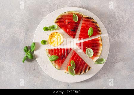 Gegrillte Wassermelonenscheiben mit Zitrone und Basilikum. Sommerdessert Stockfoto