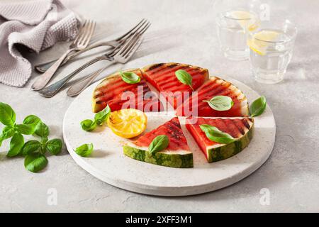 Gegrillte Wassermelonenscheiben mit Zitrone und Basilikum. Sommerdessert Stockfoto
