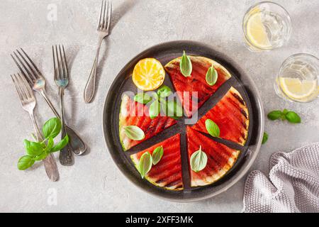Gegrillte Wassermelonenscheiben mit Zitrone und Basilikum. Sommerdessert Stockfoto