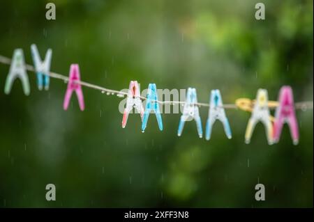 Regentropfen hängen während eines Regenschauers an Wäscheklammern einer Wäscheleine in einem Garten. Rottweil Baden-Württemberg Deutschland *** Regentropfen hängen an Kleiderschränken an einer Wäscheleine in einem Garten Rottweil Baden-Württemberg Deutschland bei einem Regenschauer Stockfoto