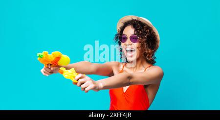 Frau, Die Wasserpistolen Vor Blauem Hintergrund Hält Stockfoto