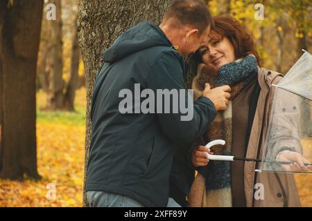 Glückliches verheiratetes Paar, das über 50 Jahre alt ist, spaziert im Herbst an einem warmen sonnigen Tag durch den Park und verbringt einen gemeinsamen Tag. Stockfoto