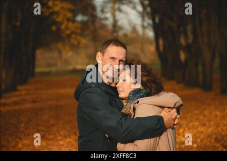 Ein verheiratetes Paar über 50 Jahre alt, spaziert im Herbst im Park an einem warmen, sonnigen Tag, umarmt, verbringt einen gemeinsamen Tag. Stockfoto