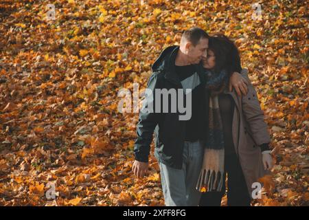 Glückliches verheiratetes Paar über 50, das sich beim Gehen umarmt, Herbst an einem warmen, sonnigen Tag, ein Wochenende zusammen verbringen. Stockfoto