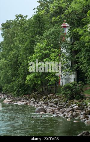 Alter Leuchtturm am Meer zwischen Bäumen Stockfoto