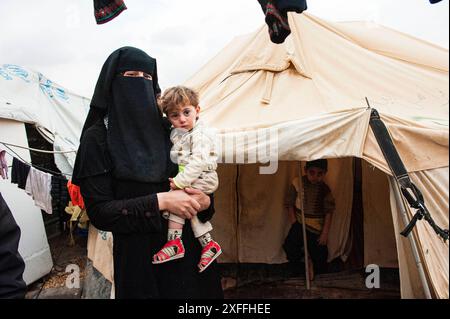 Flüchtlingsfrau mit Kind Burqa trägt Flüchtlingsfrau und Mutter mit zwei Kindern vor ihrem UNHCR-Zelt im Al Za atari Flüchtlingslager in Al Mafraq, Jordanien. Berlin Al Za atari, Al Zaatari, Zaatari Al Mafraq Deutschland Copyright: XGuidoxKoppesxPhotox Stockfoto