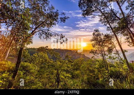 Ein atemberaubender Sonnenuntergang strahlt einen goldenen Glanz über den berühmten Felsformationen der Three Sisters in den Blue Mountains in Australien aus. Stockfoto