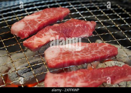 Rohes Rindfleisch auf Holzkohlegrill, Nahaufnahme von rohem Rindfleisch auf Holzkohlegrill Stockfoto