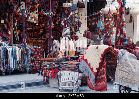 Mädchen, das vor einem traditionellen Kunsthandwerksladen sitzt, Shiraz, Iran. Stockfoto