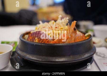 Koreanischer Eintopf mit frischen Meeresfrüchten wie Venusmuscheln und Garnelen sowie Crown Gänseblümchen und Pilzen Stockfoto
