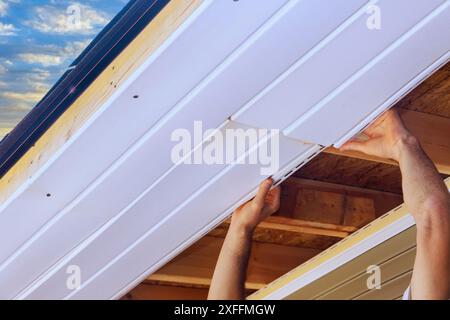 Installation von Kunststoffplatten aus Vinyl-Soffit an der Decke des neuen Wohnhauses Stockfoto