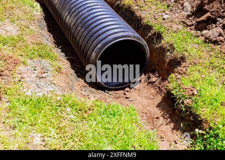 Der Wasserfluss wird durch schwarze Kunststoffrohre zum Regenwassersammelsystem geleitet Stockfoto