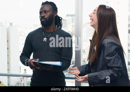Frau und Mann Kollegen im Büro schauen mit komischem Ausdruck zur Seite, der Mann hält eine Mappe und hat Dreadlocks und Bart. Stockfoto