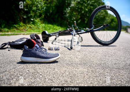 Torbole, Gardasee, Italien - 30. Juni 2024: Symbolisches Bild eines Verkehrsunfalls mit einem Fahrrad. Fahrradunfall mit Fahrrad auf der Straße und vom Radfahrer verstreuten Objekten *** Symbolbild Verkehrsunfall mit einem Fahrrad. Fahrradunfall mit Rad auf der Straße und verstreuten Gegenstände von dem Radfahrer gestellte Szene Stockfoto