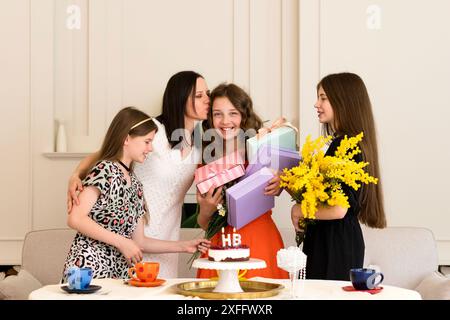 Freunde feiern Geburtstag mit einem Kuchen, Geschenken und Blumen. Mädchen feiern Stockfoto