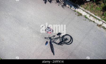 Torbole, Gardasee, Italien - 30. Juni 2024: Symbolisches Bild eines Verkehrsunfalls mit einem Fahrrad. Fahrradunfall mit Fahrrad auf der Straße und vom Radfahrer verstreute Objekte posierte Szene Luftbild *** Symbolbild Verkehrsunfall mit einem Fahrrad. Fahrradunfall mit Rad auf der Straße und verstreuten Gegenstände von dem Radfahrer stellte Szene Luftaufnahme Stockfoto