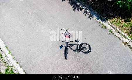 Torbole, Gardasee, Italien - 30. Juni 2024: Symbolisches Bild eines Verkehrsunfalls mit einem Fahrrad. Fahrradunfall mit Fahrrad auf der Straße und vom Radfahrer verstreute Objekte posierte Szene Luftbild *** Symbolbild Verkehrsunfall mit einem Fahrrad. Fahrradunfall mit Rad auf der Straße und verstreuten Gegenstände von dem Radfahrer stellte Szene Luftaufnahme Stockfoto