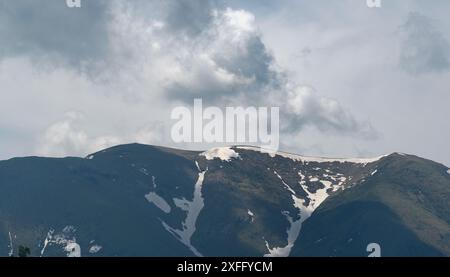 Schneebedeckte Berggipfel unter bewölktem Himmel. Stockfoto