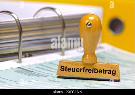 Steuerfreibetrag und Grundfreibetrag auf einem Aktenordner mit Formularen steht ein Holzstempel mit dem Aufdruck: Steuerfreibetrag *** Stockfoto