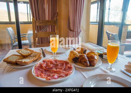 Frühstück in einem Landhotel: Orangensaft, Schinken, Kuchen und Brot. Stockfoto