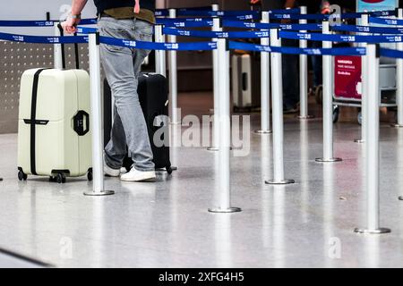 03. Juli 2024, Nordrhein-Westfalen, Düsseldorf: Ein Passagier geht mit seinen Koffern zu einem Check-in-Schalter am Flughafen. Foto: Christoph Reichwein/dpa Stockfoto