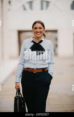 Die lächelnde Latina-Geschäftsfrau schreitet selbstbewusst durch die Straßen der Stadt. Stockfoto