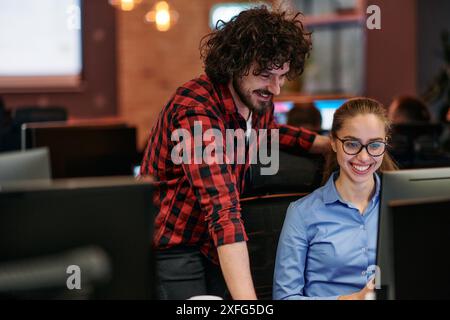 Geschäftskollegen, ein Mann und eine Frau, diskutieren über Geschäftsstrategien und blicken aufmerksam auf einen Computermonitor und verkörpern damit Stockfoto